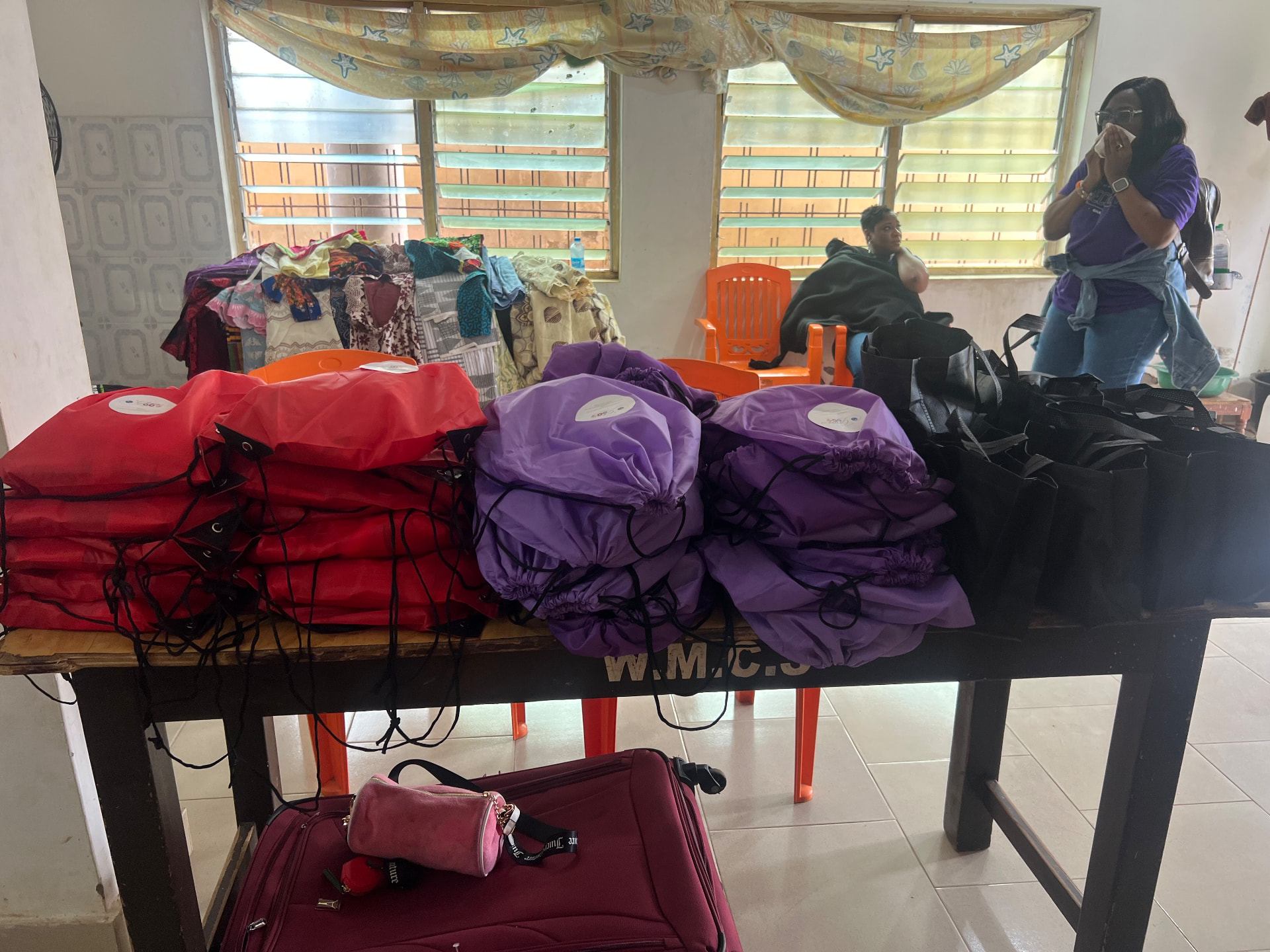 Care packages in red, purple and black drawstring bags prepared for distribution in Ghana